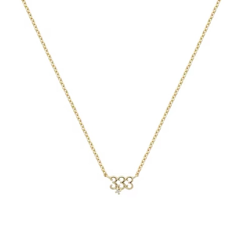 May include: A gold chain necklace with a pendant featuring the number 333 with a small diamond accent.