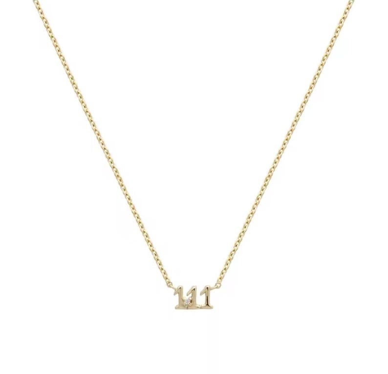 May include: A gold chain necklace with a pendant featuring the number 111 with a small diamond in the center.
