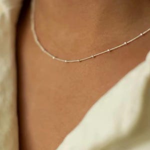 May include: A delicate silver necklace with tiny beads, perfect for layering or wearing alone.