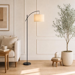 May include: A tall floor lamp with a thin black metal stand and a curved arm holding a cylindrical beige fabric lampshade. The lamp features a circular black base and emits a warm, soft glow from the light source within the shade.
