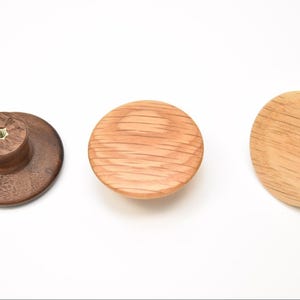 May include: Three wooden knobs, one dark brown, one light brown, and one medium brown. The knobs are round and have a slightly raised center.