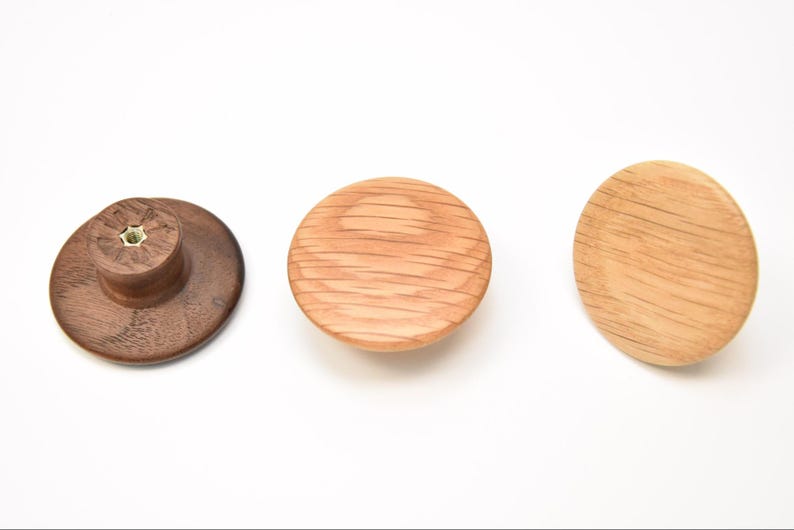 May include: Three wooden knobs, one dark brown, one light brown, and one medium brown. The knobs are round and have a slightly raised center.