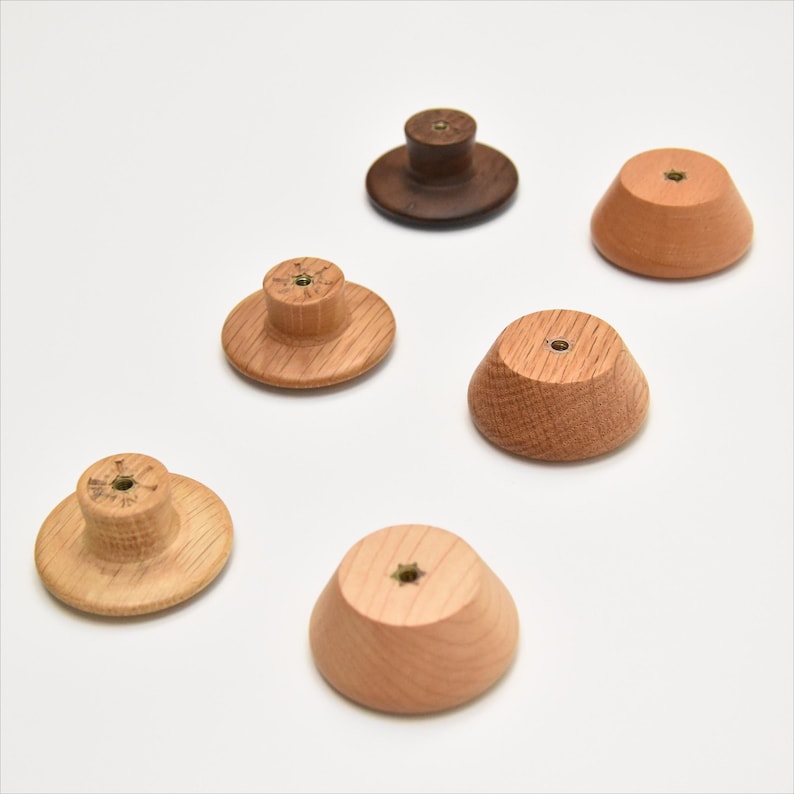 May include: Six wooden knobs in various shapes and sizes. The knobs are made of light and dark wood and have a brass screw in the center.