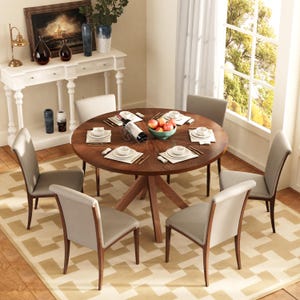 May include: A round wooden dining table with six gray upholstered chairs. The table is set with white plates, placemats, and silverware. A bowl of apples and a wine bottle are in the center. The room has a neutral color palette.
