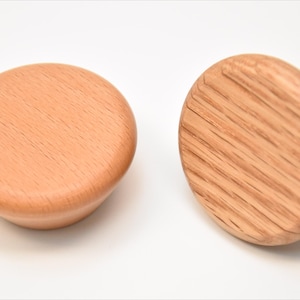 May include: Two wooden knobs with a natural finish. One knob has a smooth surface, while the other has a grooved surface.