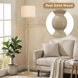 May include: A floor lamp with a light-colored, cylindrical fabric shade and a tall, slender stand composed of stacked wooden spheres. The base is a flat, circular wooden disc. A circular inset highlights the texture of the real solid wood.