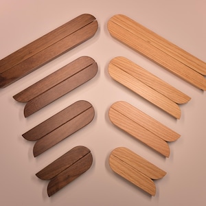 May include: Set of eight wooden coasters in two different wood tones. The coasters are shaped like a pair of wings, with a rounded edge and a flat base.