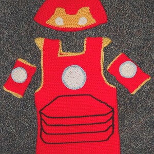 May include: A red, yellow and white crocheted Iron Man costume for a baby or toddler. The costume includes a hat, vest and arm pieces.
