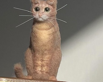 Könnte beinhalten: Eine Nadelfilz-Katzenfigur mit einem hellbraunen und weißen Fell, die auf einem Holzsockel mit einer goldenen Plakette steht, auf der "bunny" steht.