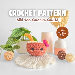 May include: A crochet pattern for "Kiki the Coconut Cocktail" is shown. The image features a cute, smiling, crocheted coconut cocktail with an orange straw and a pink flower. The text "CROCHET PATTERN" is at the top.