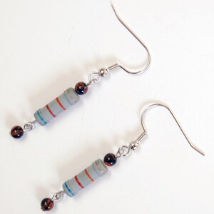 May include: A pair of silver earrings with a gray resistor and brown beads. The resistor has red and blue stripes.