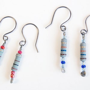 May include: A pair of earrings with gray ceramic resistor beads and colorful beads. The earrings have silver hooks.