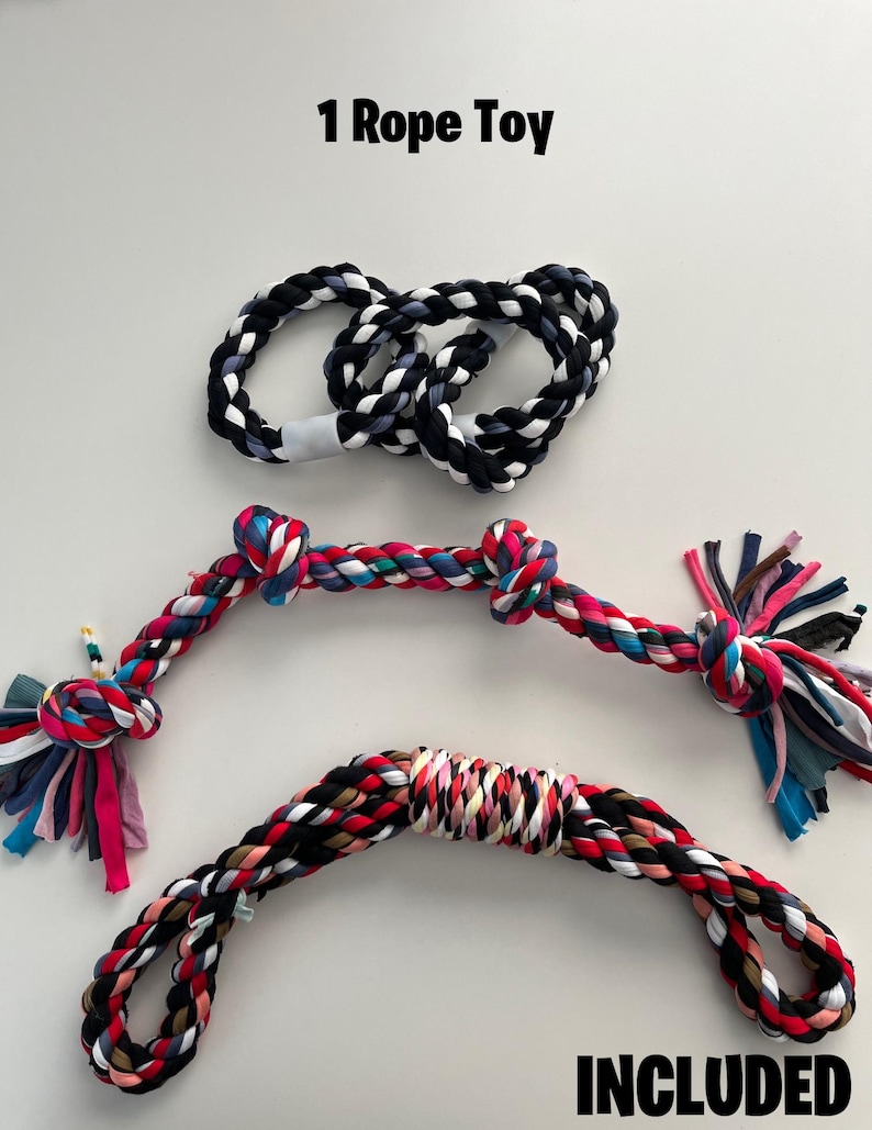 Op de afbeelding: Drie kleurrijke touwspeelgoed voor honden. Een touwspeelgoed is zwart-wit, een is rood, roze, zwart en wit, en de andere is veelkleurig. De tekst "INCLUDED" is geschreven in witte letters op een zwarte achtergrond aan de onderkant van de afbeelding. De tekst "1 Rope Toy" is geschreven in zwarte letters aan de bovenkant van de afbeelding.
