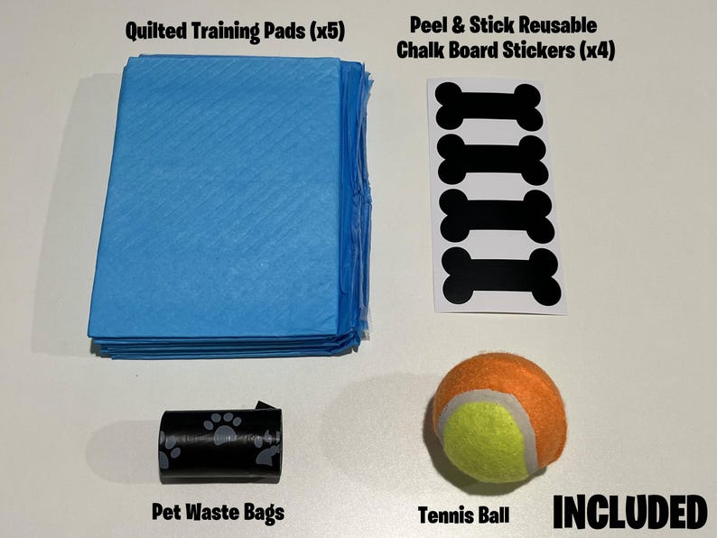 Op de afbeelding: Een set hondentrainingsproducten, inclusief vijf blauwe, gewatteerde trainingspads, vier zwarte, botvormige krijtbord stickers, een rol zwarte huisdierpoepzakken en een gele en oranje tennisbal. De tekst "INCLUDED" is in zwart op een witte achtergrond gedrukt.