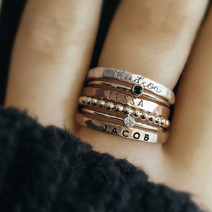 Stackable name ring collection called the maya on a models finger up close