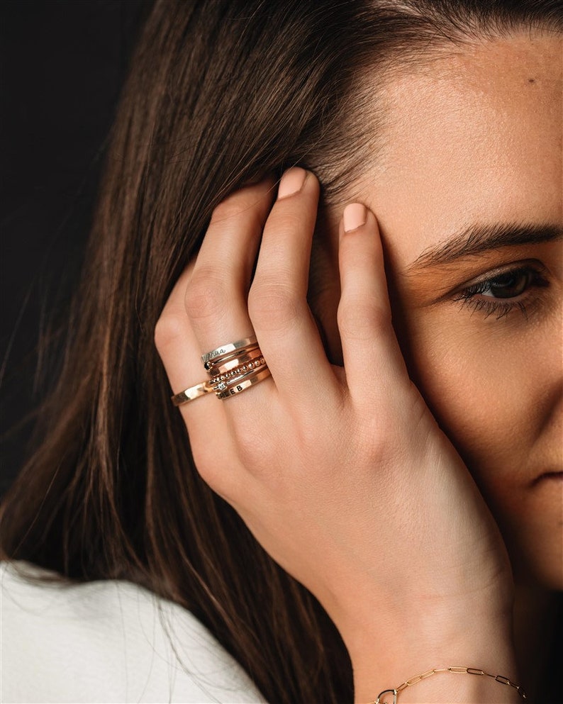 Stackable name ring collection called the maya on a models hand