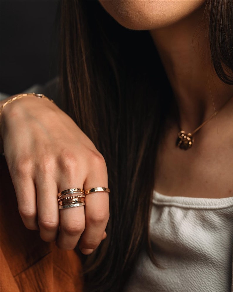 Stackable name ring collection called the maya on a models hand