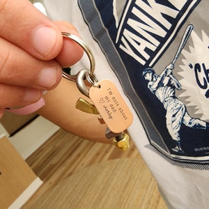 May include: A copper-colored keychain with the text "I'm nuts about my dad. Charley" and a heart symbol. The keychain features a collection of metal nuts and bolts, and a gold-colored accent piece.