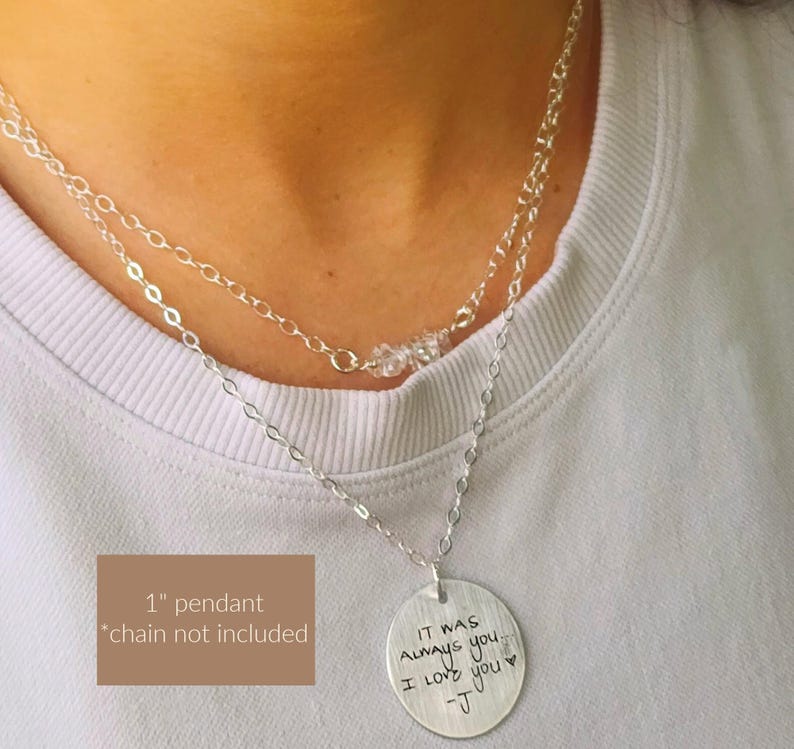 May include: A layered silver necklace with a round pendant. The pendant has the handwritten text "IT WAS ALWAYS you. I LOVE you -J". The necklace has a 1-inch pendant, and the chain is not included.