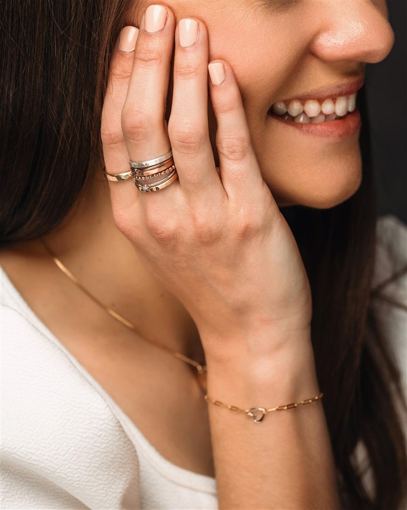 Stackable name ring collection called the maya on a models hand