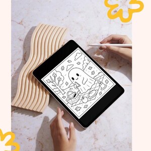 May include: A black tablet showing a black and white illustration of a ghost's picnic. The ghost is on a picnic blanket with a basket, food, and candles. A wooden decorative piece is to the left of the tablet.