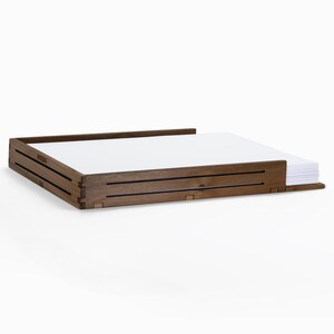 May include: A wooden desk organizer with a dark brown finish. The organizer has a slot for holding papers and a lower section for storing additional items.