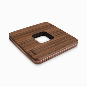 Könnte beinhalten: Ein quadratischer Untersetzer aus Holz mit einem Ausschnitt in der Mitte. Der Untersetzer ist aus Walnussholz gefertigt und hat eine hellbraune Farbe. Der Markenname "WOODSAMA" ist auf der Unterseite des Untersetzers eingraviert.