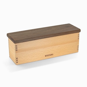 Peut inclure: Une boîte en bois avec un couvercle en noyer et une base en bois clair. La boîte porte une étiquette sur le devant qui dit "WOODSAKA".
