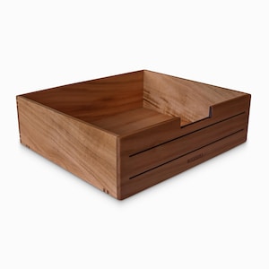 May include: A wooden box with a cutout on one side. The box is made of light brown wood with a dark brown stain. The box has a label on the front that says "WOODISAKA".