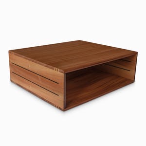 May include: A wooden coffee table with a shelf. The table is made of light brown wood with dark brown stripes.