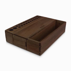 May include: A wooden organizer with multiple compartments for storing pens, pencils, and other small items. The organizer has a dark brown finish and is made of solid wood.
