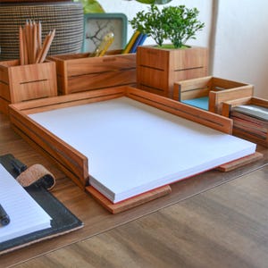 Könnte beinhalten: Ein Schreibtisch-Organizer-Set aus Holz mit einem Brieftablett, einem Stiftehalter und zwei kleinen Aufbewahrungsboxen. Das Set ist aus Naturholz mit einer hellbraunen Oberfläche gefertigt. Der Organizer steht auf einem Holztisch.