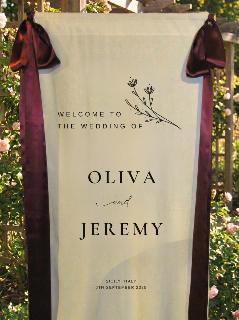 May include: A cream-colored wedding welcome sign with burgundy ribbons and the text "WELCOME TO THE WEDDING OF OLIVA and JEREMY" with floral accents. The sign also includes the location and date: Sicily, Italy, 6th September 2025.