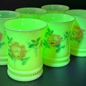 May include: A set of six vintage green glass tumblers. Each tumbler has a painted rose design in brown and green. The rims are accented with gold trim. The glasses are approximately 10 cm tall.