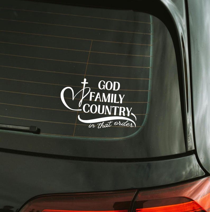 K&ouml;nnte beinhalten: Wei&szlig;er Vinyl-Aufkleber f&uuml;r ein Autofenster. Der Aufkleber zeigt die Worte "GOD FAMILY COUNTRY" in einer stilisierten Schriftart, mit einem Kreuz- und Herzsymbol. Der Satz "in that order" steht darunter.