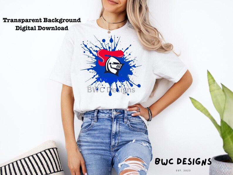 May include: A white t-shirt with a blue and red knight helmet graphic in a blue paint splatter design. The text "BWC Designs" is visible on the shirt.