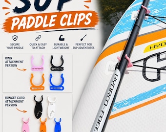 May include: SUP paddle clips in various colors including pink, black, orange, blue, and white. The image displays ring attachment and bungee cord attachment versions, with a pink clip secured to a black paddle on a white, blue, and orange board.