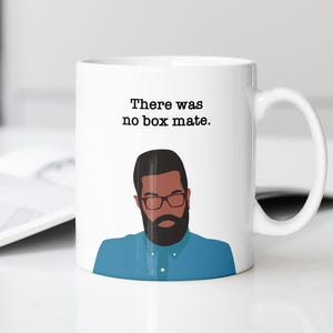 May include: White ceramic mug with a black and white illustration of a man with a beard and glasses. The mug has the text "There was no box mate." printed on it.
