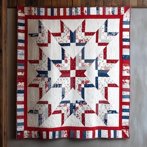 May include: A large, handmade quilt with a starburst design. The quilt features a white background with red and blue star patterns. The border is red with blue and white stripes. The quilt is hanging on a wooden wall.