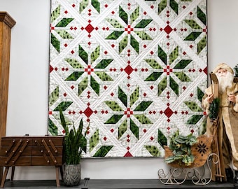 May include: A square quilt featuring a repeating star pattern in shades of green, white, and red. The design consists of large geometric star shapes with white background panels, accented by small red squares at the intersections of the white borders.
