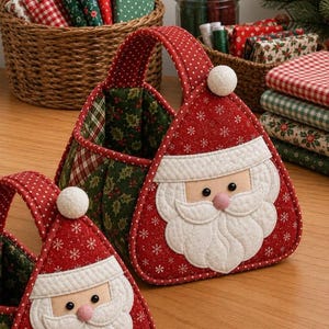 May include: A quilted fabric basket featuring a Santa Claus face on the front with a red hat adorned with white snowflakes and a white pom-pom. The interior and sides are lined with green fabric featuring a holly leaf pattern and red plaid accents.