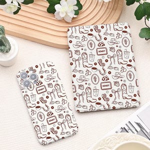 Peut inclure: Une coque de smartphone blanche et une coque de tablette assortie présentant un motif répétitif de lignes marron représentant des bottes de cow-boy, des chapeaux, des nœuds, des cerises, des papillons et des étiquettes avec le texte HOWDY.
