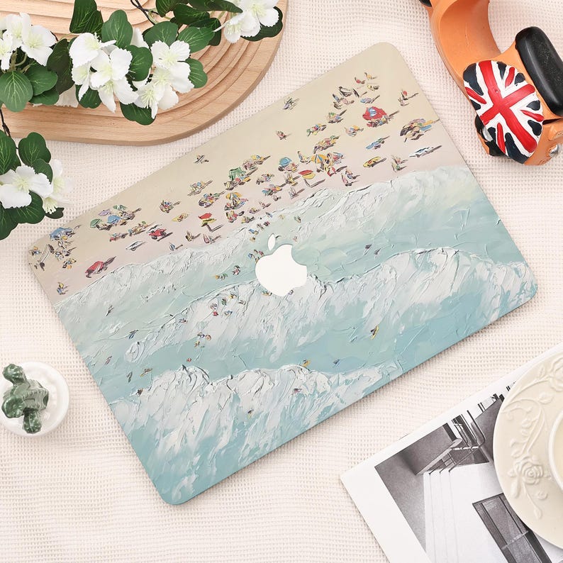 K&ouml;nnte beinhalten: Eine Laptop-H&uuml;lle mit einer k&uuml;nstlerischen Strandszene, die einen hellblauen Ozean und einen sandigen Strand zeigt. Das Design umfasst kleine Figuren und Sonnenschirme, mit einem wei&szlig;en Apple-Logo. Die H&uuml;lle ist ein sch&uuml;tzendes Zubeh&ouml;r.
