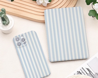 Puede incluir: Una funda rectangular para tableta y una funda para teléfono inteligente, ambas con un patrón de rayas verticales en azul claro y blanco. La funda del teléfono incluye un recorte para un sistema de cámara de múltiples lentes.