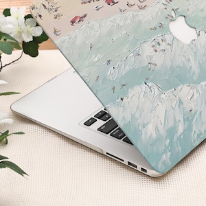 K&ouml;nnte beinhalten: Ein Laptop mit einer dekorativen H&uuml;lle, die eine abstrakte Strandszene zeigt. Die H&uuml;lle hat ein strukturiertes, gemaltes Aussehen mit hellblauen, wei&szlig;en und beigen Farben. Das Design umfasst Figuren und Wellen und schafft ein K&uuml;stenmotiv.