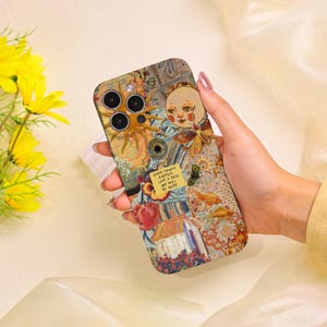 以下が含まれることがあります： 太陽、月、花、魚など、コラージュデザインが施されたカラフルな携帯電話ケース。ケースはテクスチャ加工が施されており、「GOOD THINGS HAPPEN, LOVE IS REAL, WE WILL BE OKAY.」の文字が含まれています。