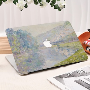 Pode incluir: Um laptop com um design de pintura de paisagem na capa. A obra de arte apresenta uma cena de rio com &aacute;rvores e montanhas, renderizada em suaves azuis, verdes e amarelos. O logotipo da Apple &eacute; vis&iacute;vel.