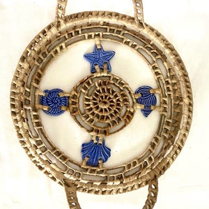 May include: Woven natural fiber tray with two handles. The tray features a central spiral design and is adorned with blue ceramic starfish, seashells, and other sea-themed elements. The tray is round and has a diameter of approximately 12 inches.