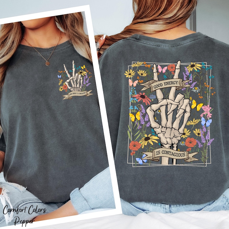 a gray t-shirt with a graphic design on the back, depicting a skeleton hand making a peace sign with flowers and butterflies.