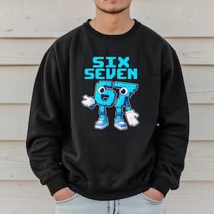 A man wearing a black sweatshirt with a graphic design featuring a blue character and the text "Six Seven" printed on it.